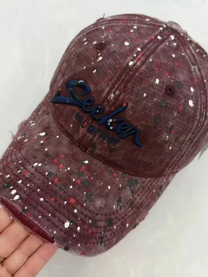 A deep red baseball cap covered in small rhinestones with a script motif across the front