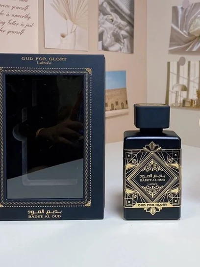 A dark fragrance bottle standing in an open presentation box with a printed inner lid