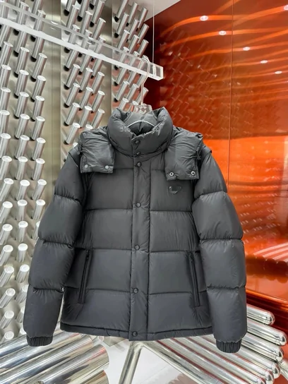 A grey hooded puffer jacket on a rail, lit by orange light from the display behind it