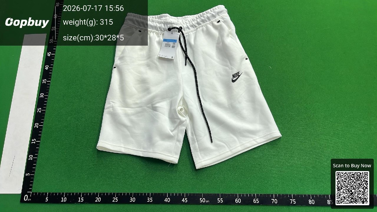 White shorts with a hanging label and black drawstring on an Oopbuy green measuring mat